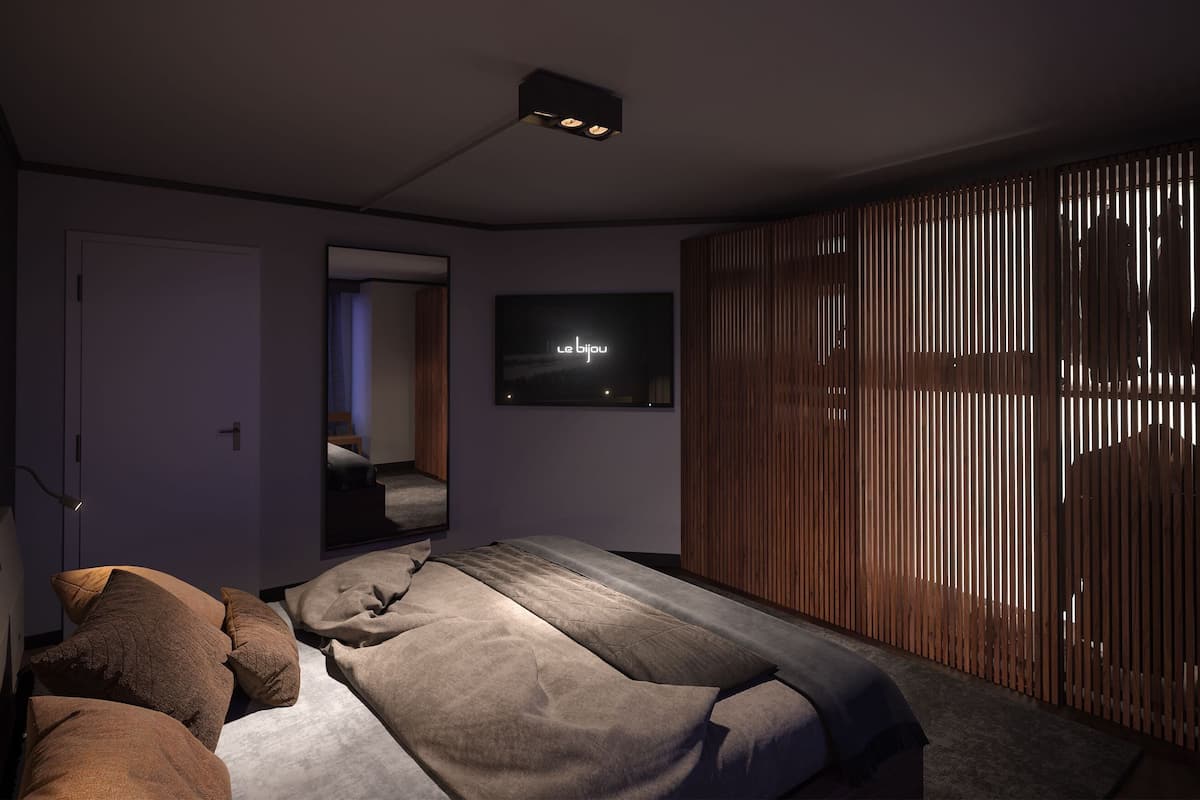 A modern bedroom with a bed, a TV, and a sliding wooden door.