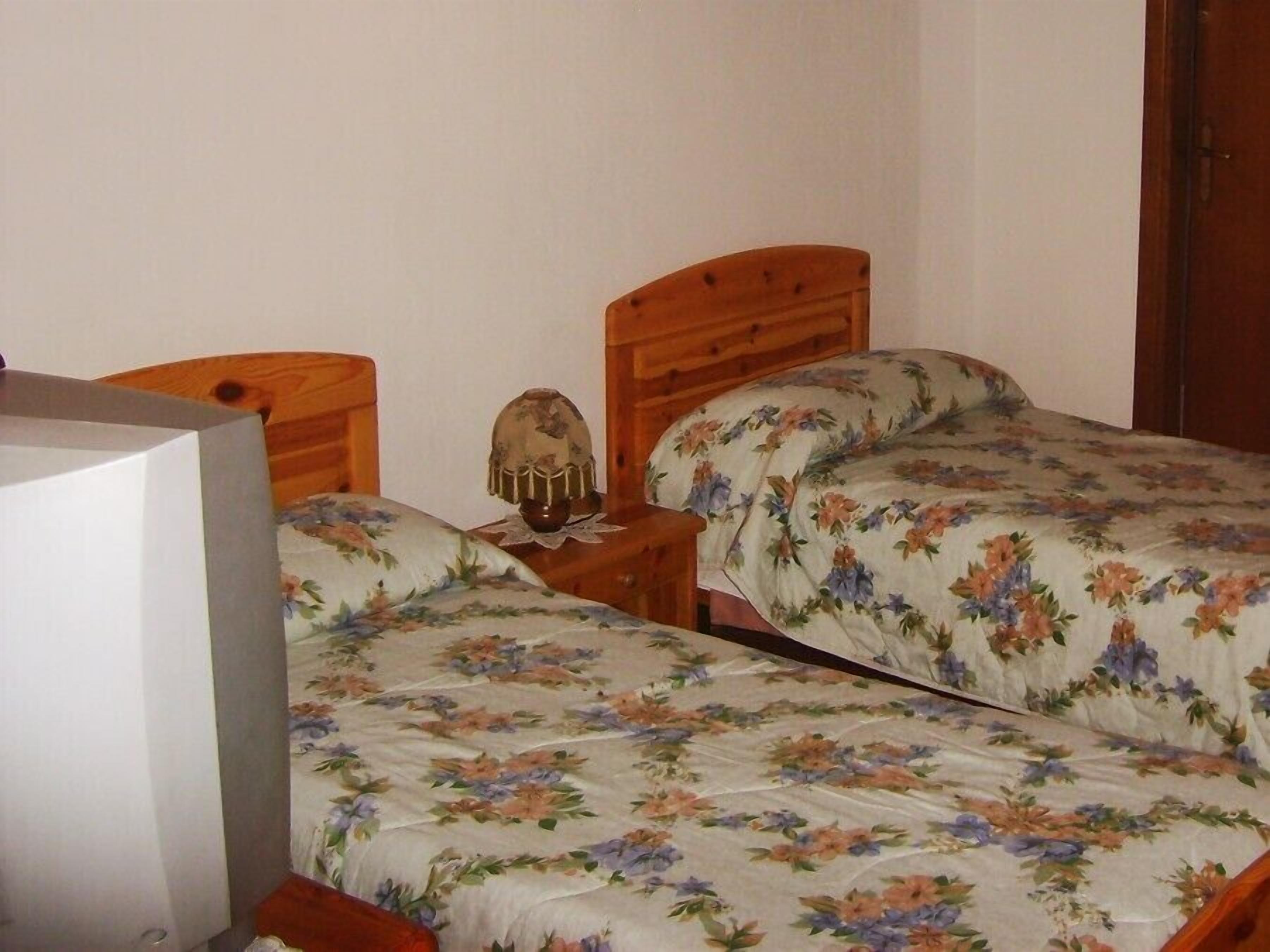 Une chambre à coucher avec deux lits en bois, une table de chevet, une lampe et un téléviseur.
