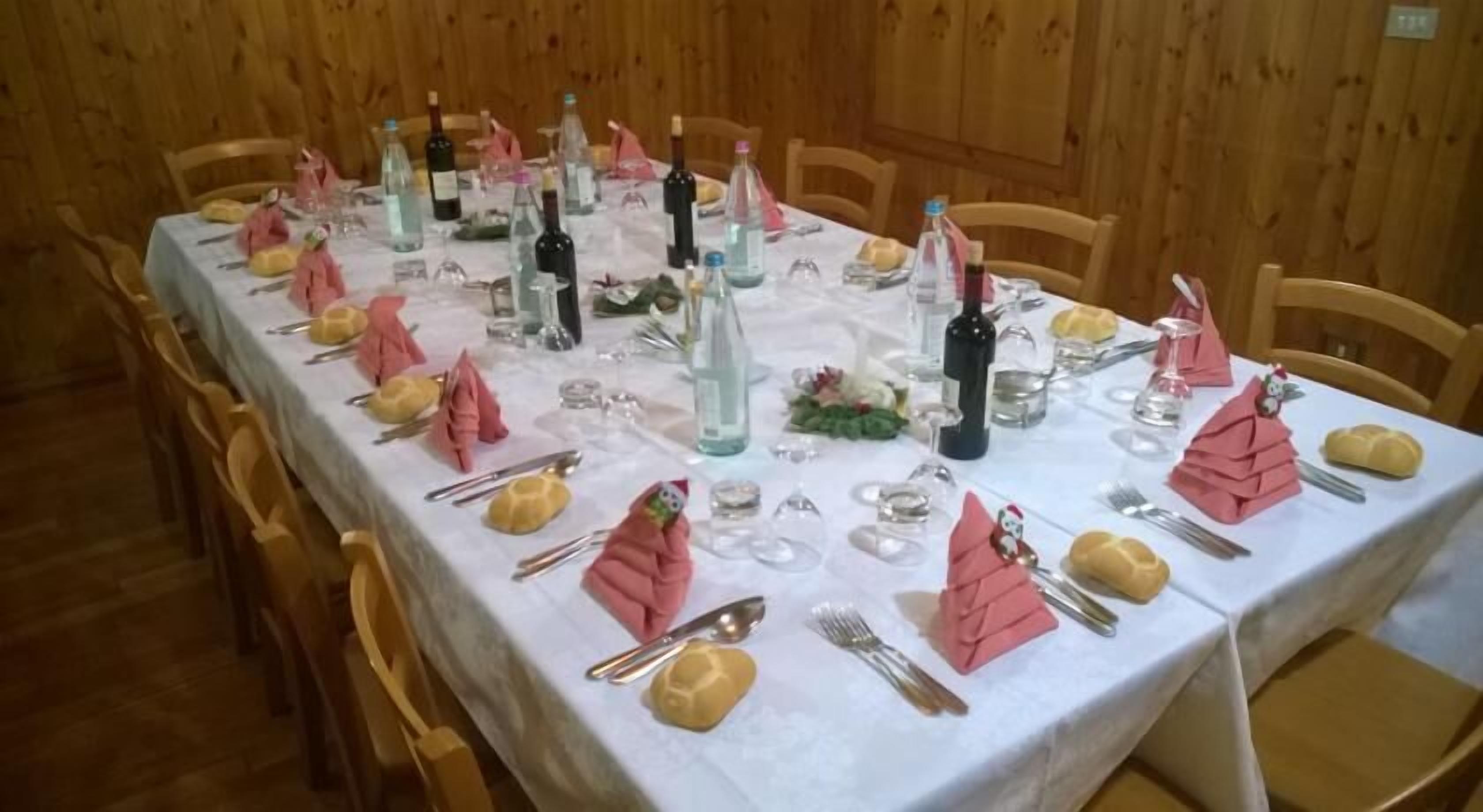 A long dining table set with multiple wine bottles, glasses, and folded napkins.