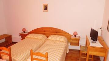 Un dormitorio con dos camas, un escritorio, una silla, un televisor y lámparas de noche.