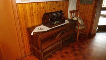 A wooden dresser with a radio, a chair, and a framed picture on the wall.