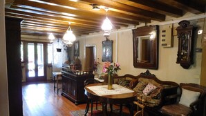 A traditional room with wooden floors, a dining table with chairs, a sofa, and a large mirror.