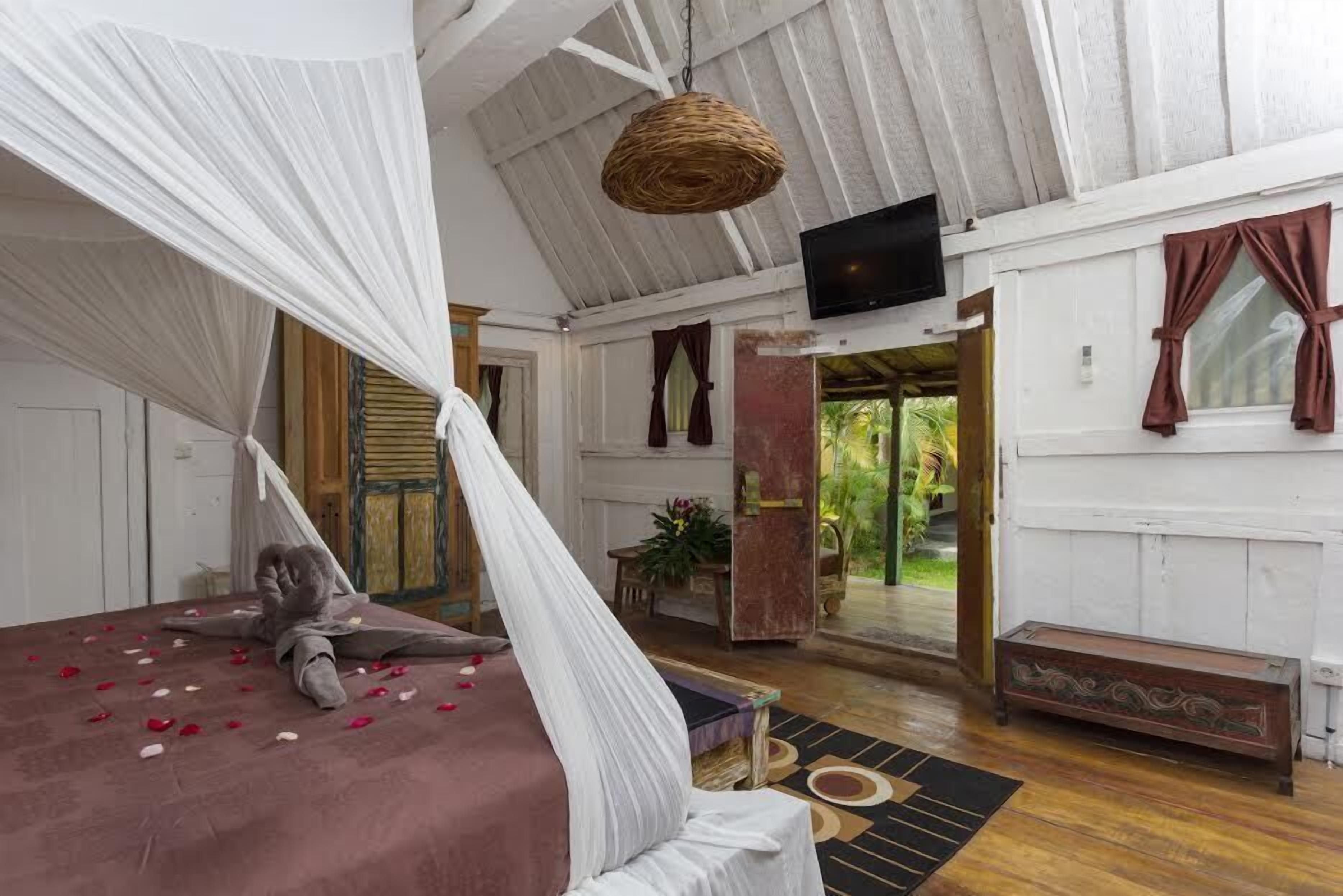 Ein Schlafzimmer mit Baldachinbett, Fernseher und Blick auf den Garten.
