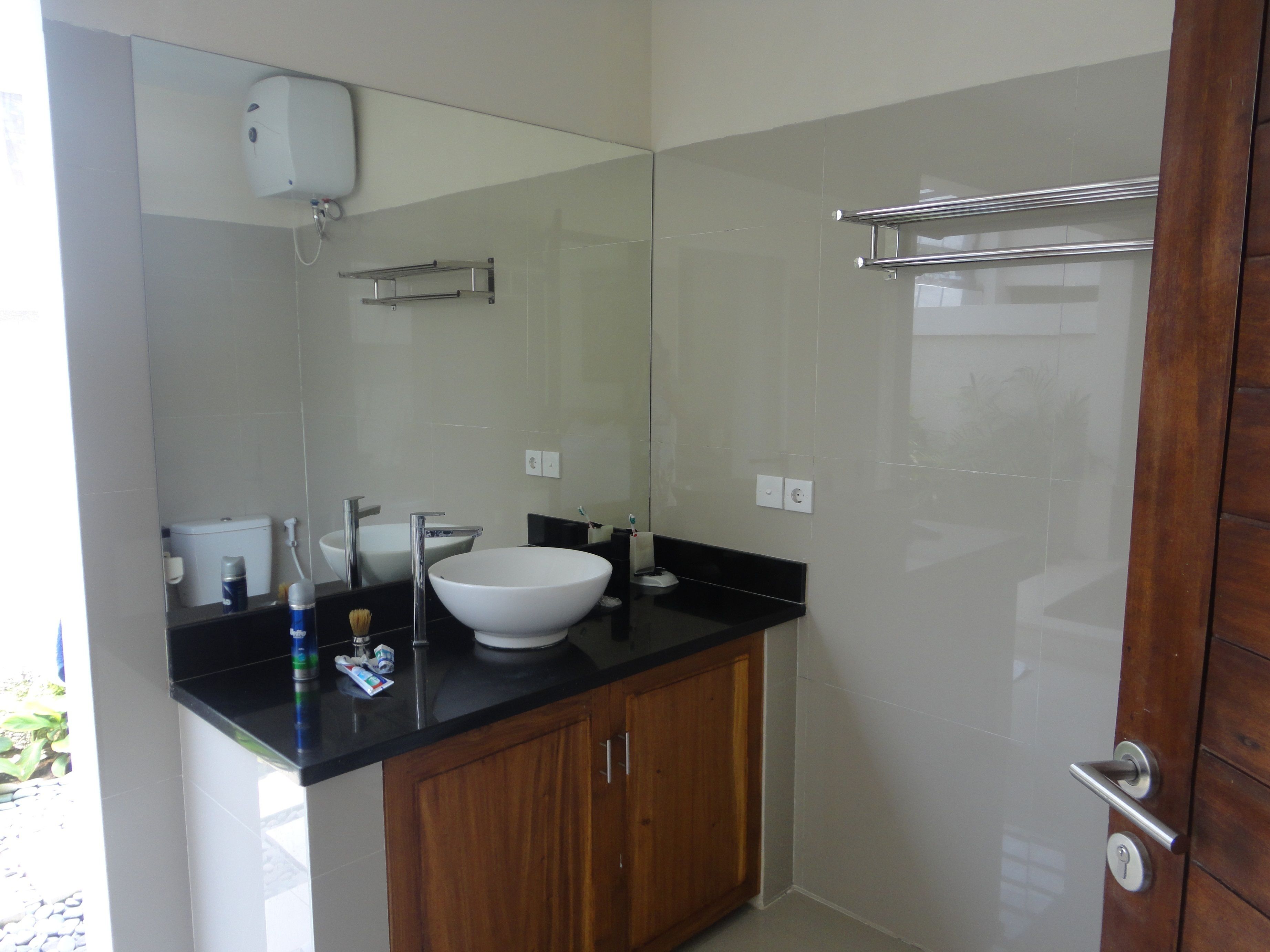 Un baño con un lavabo blanco, un espejo, un perchero para toallas y un armario de madera.