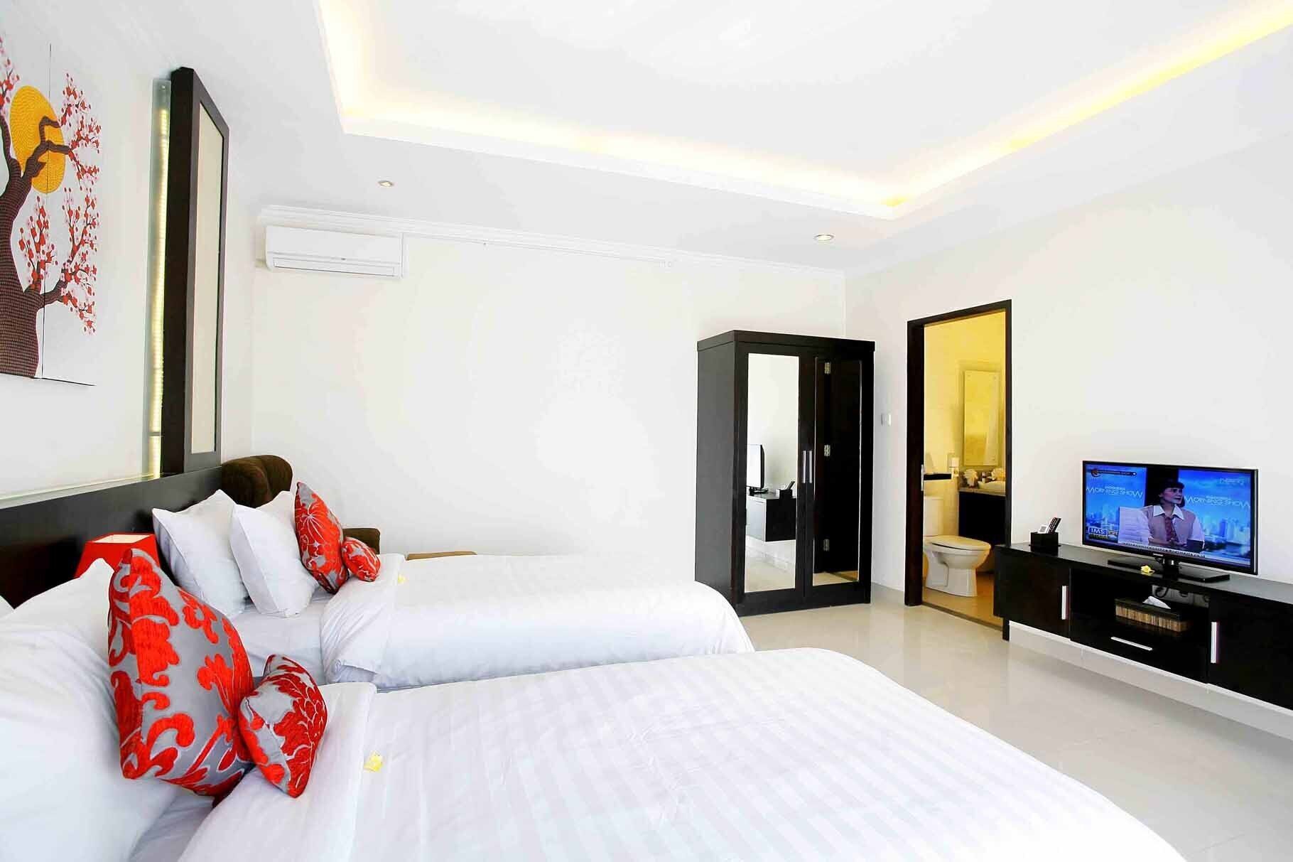 A modern hotel room with two beds, a TV, and a bathroom visible through an open door.