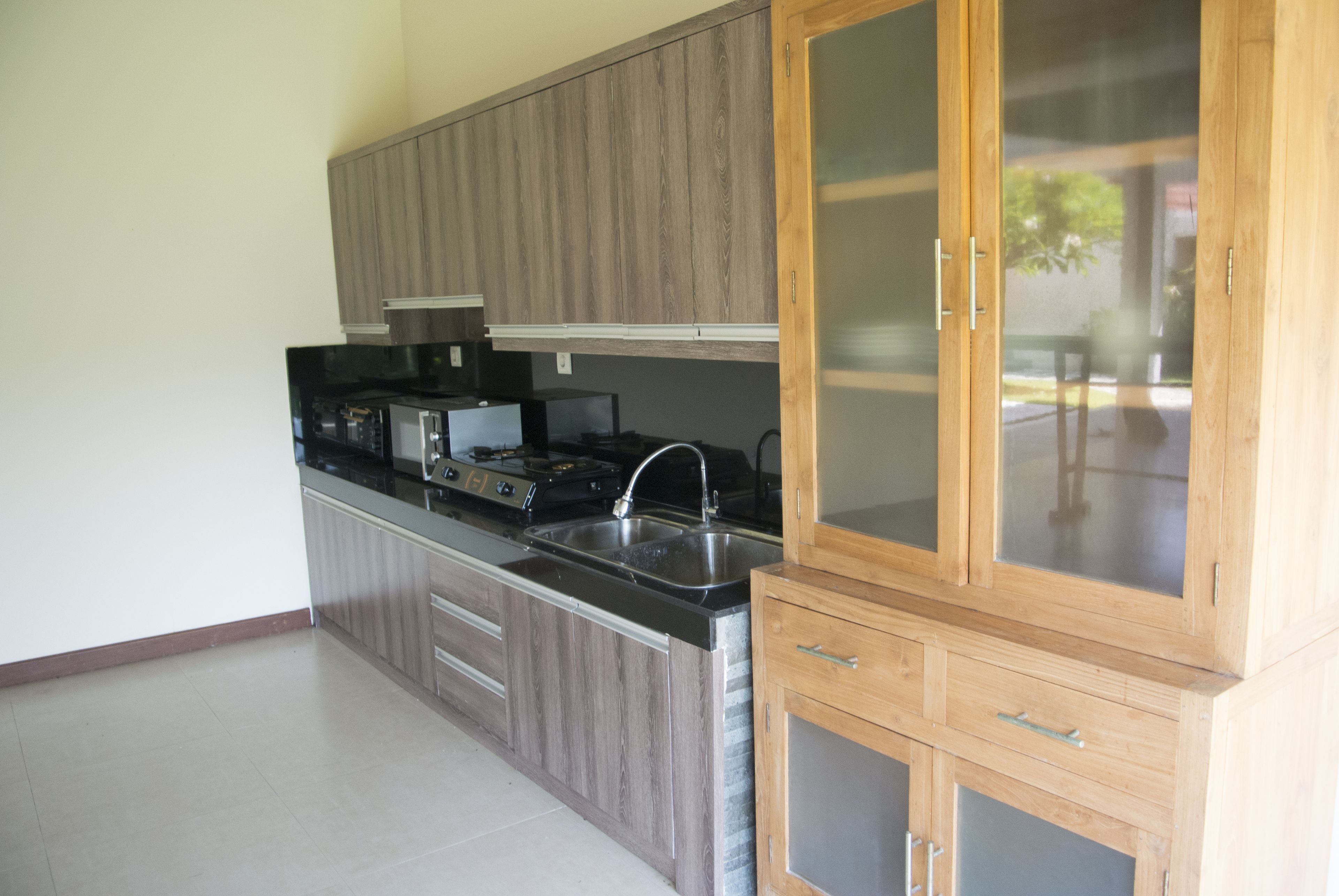 Una cocina con armarios de madera, encimera negra, electrodomésticos de acero inoxidable y un mueble con puertas de vidrio.