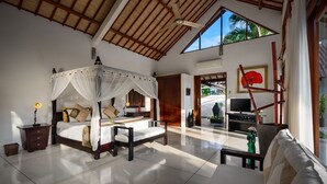A spacious bedroom with a canopy bed, a desk with a lamp, and a TV. - Villa Dewi (Seminyak)