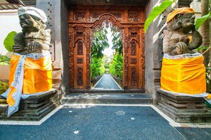 A temple entrance with ornate wooden doors and statues on either side. - Villa Dewi (Seminyak)