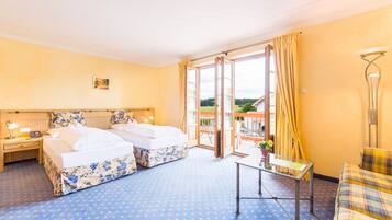 A hotel room with two beds, a balcony, a small table, and a sofa.