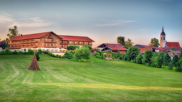A large building with multiple balconies and a prominent tower, surrounded by well-maintained lawns and trees. - Hotel und Landgasthof Altwirt (Holzkirchen)