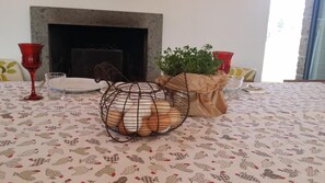 Een eettafel met een tafelkleed met dessin, een metalen mand met een plant en rode glazen aan weerszijden.