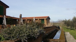 Un edificio rústico con techo de tejas y un estrecho canal de agua a su lado.