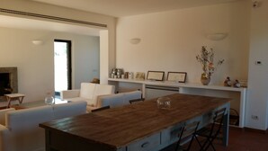 Una cocina moderna con una isla de madera, muebles blancos y un comedor.