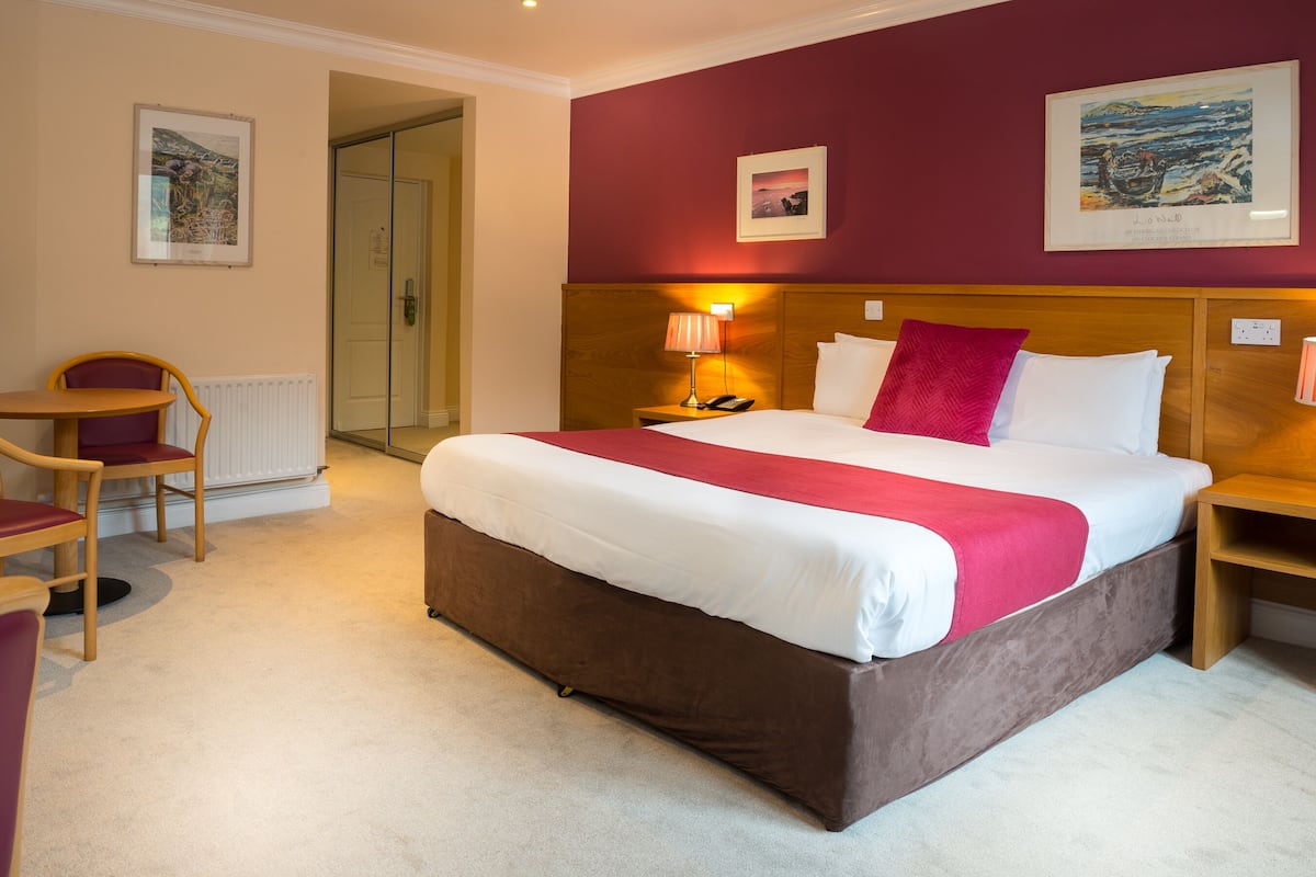 A hotel room with a large bed, a desk, and a chair.