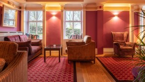 Una habitación con alfombra roja, un sofá, una silla y una mesa.