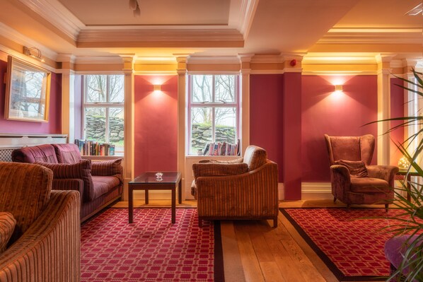 Una habitación con alfombra roja, un sofá, una silla y una mesa.