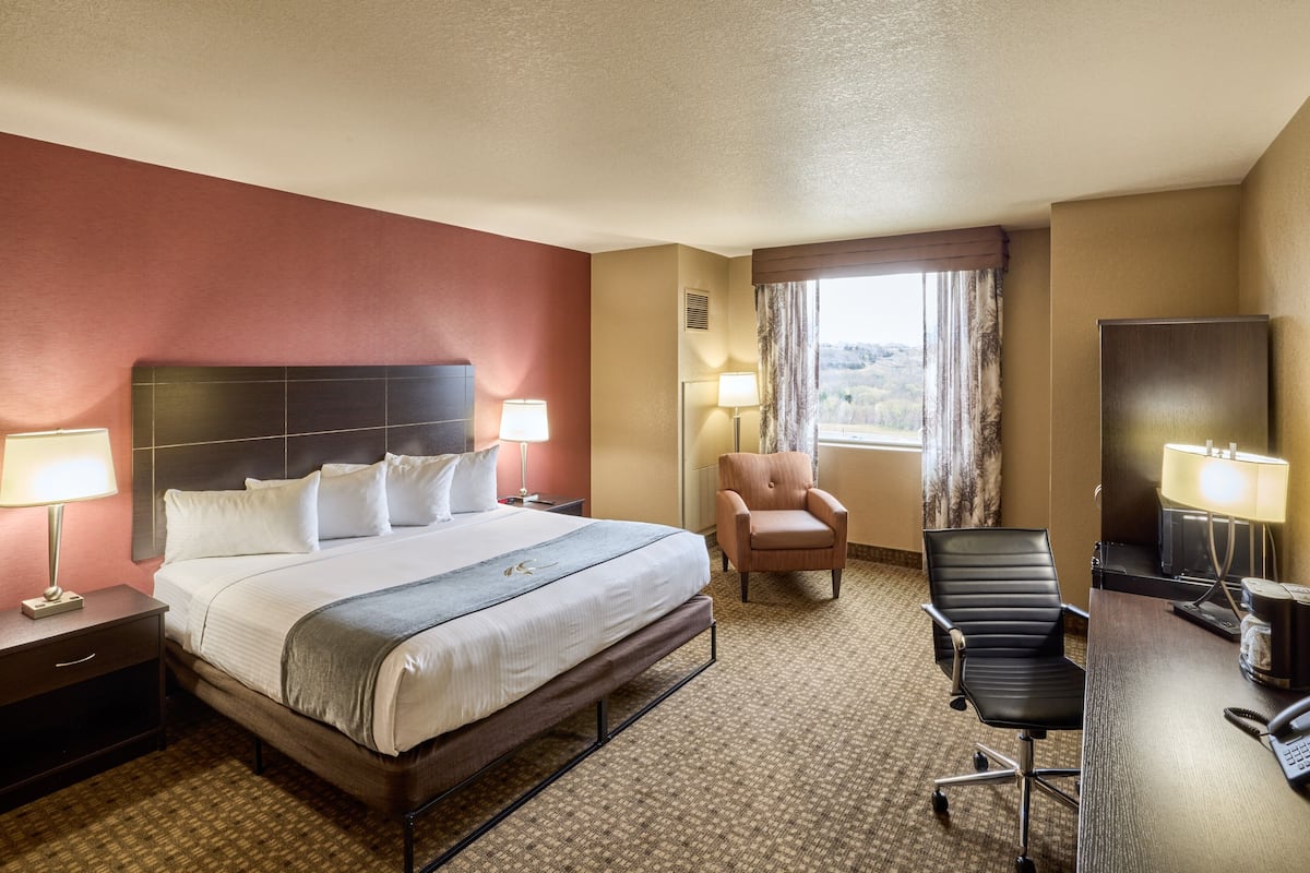 A hotel room with a bed, a desk, a chair, and a television.