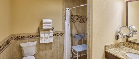 A bathroom with a toilet, shower, and sink.