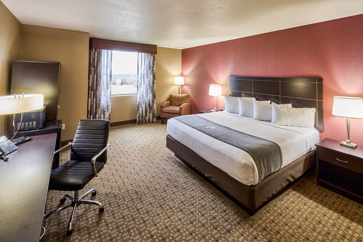 A hotel room with a bed, desk, chair, and two lamps.