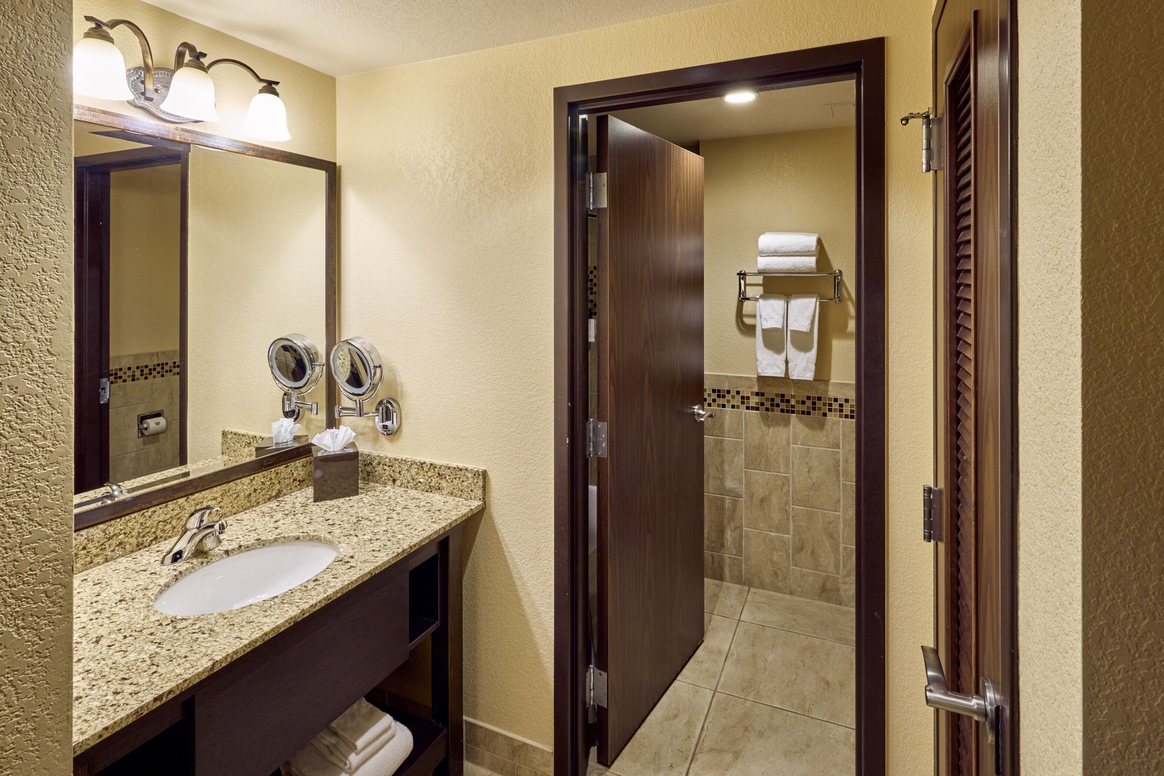 A bathroom with a sink, mirror, towel rack, and shower area.