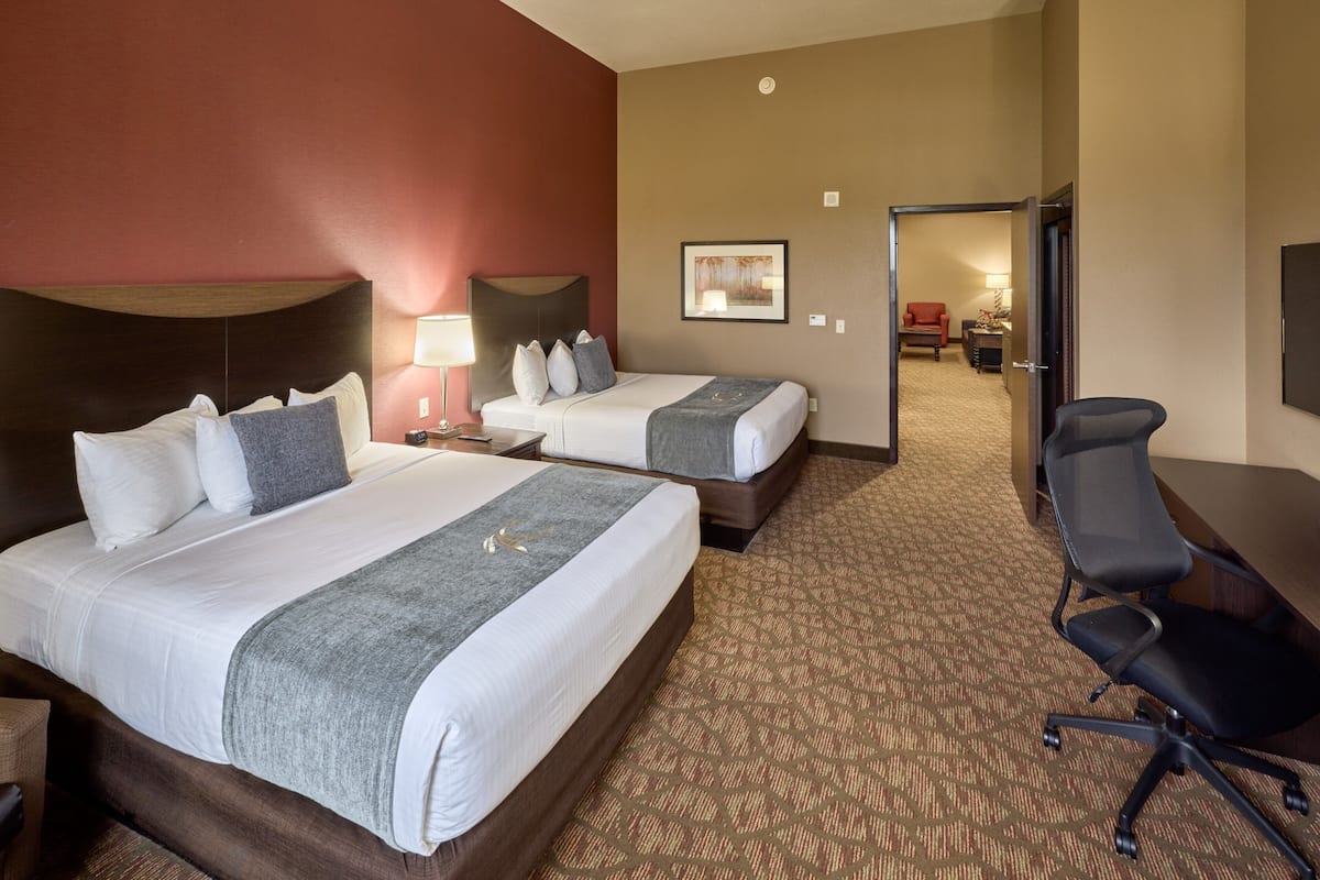 A hotel room with two beds, a desk, and a chair.