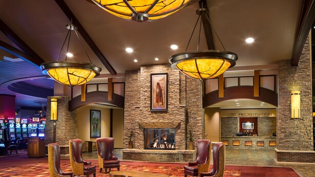 A lobby with a stone fireplace, leather armchairs, and a registration desk. - Choctaw Casino & Resort Pocola, Trademark Coll by Wyndham (Pocola)