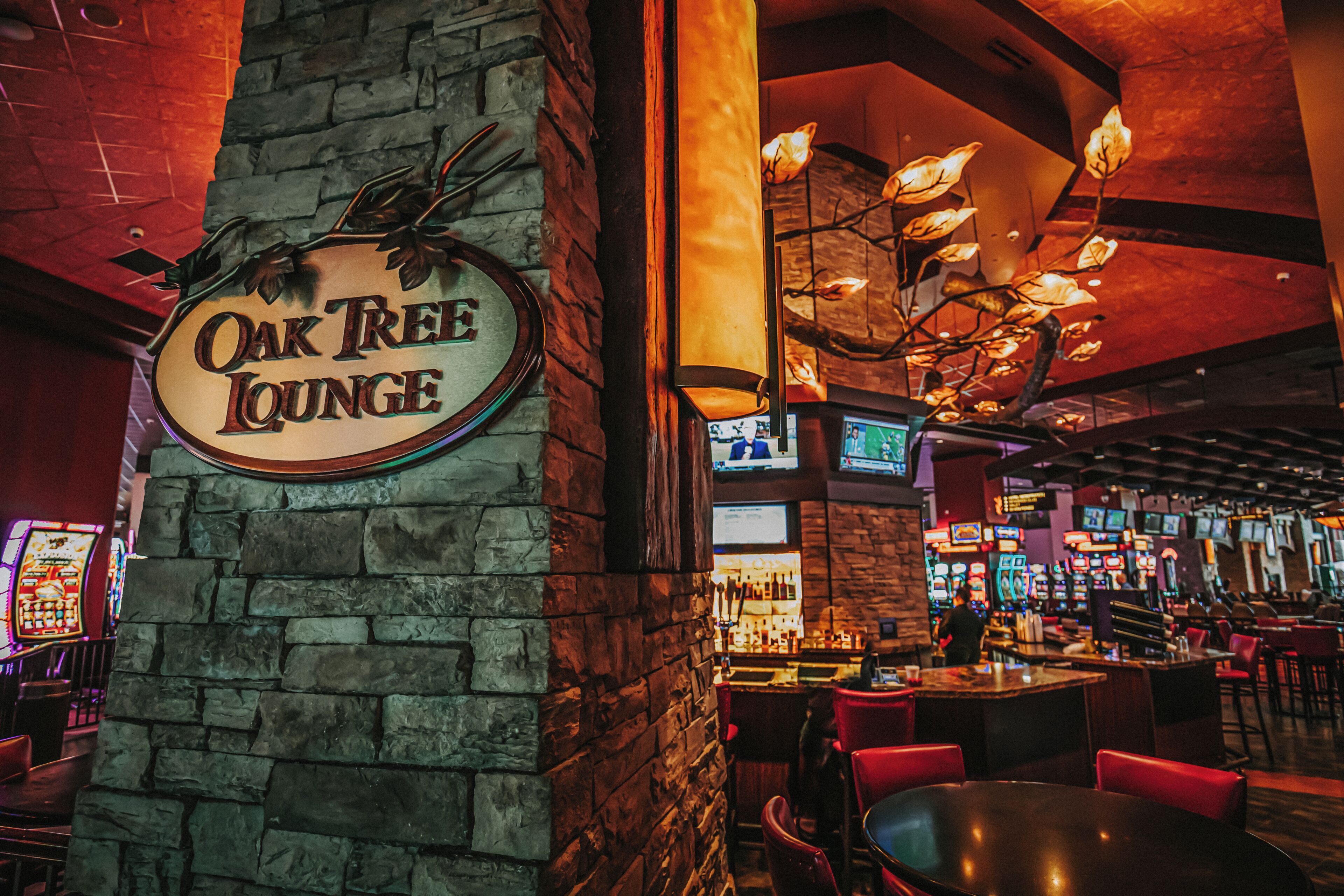 A bar area with a stone pillar, a sign reading 'Oak Tree Lounge,' and a variety of gaming machines.