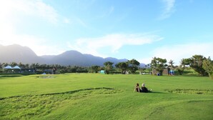 A grassy field with a few people, tents, and a building in the background. - Fu Taitung B&B (Taitung)