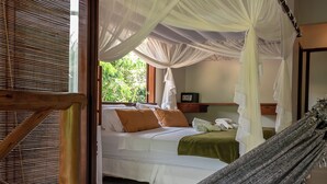 A bedroom with a bed, a hanging hammock, and a canopy bed.