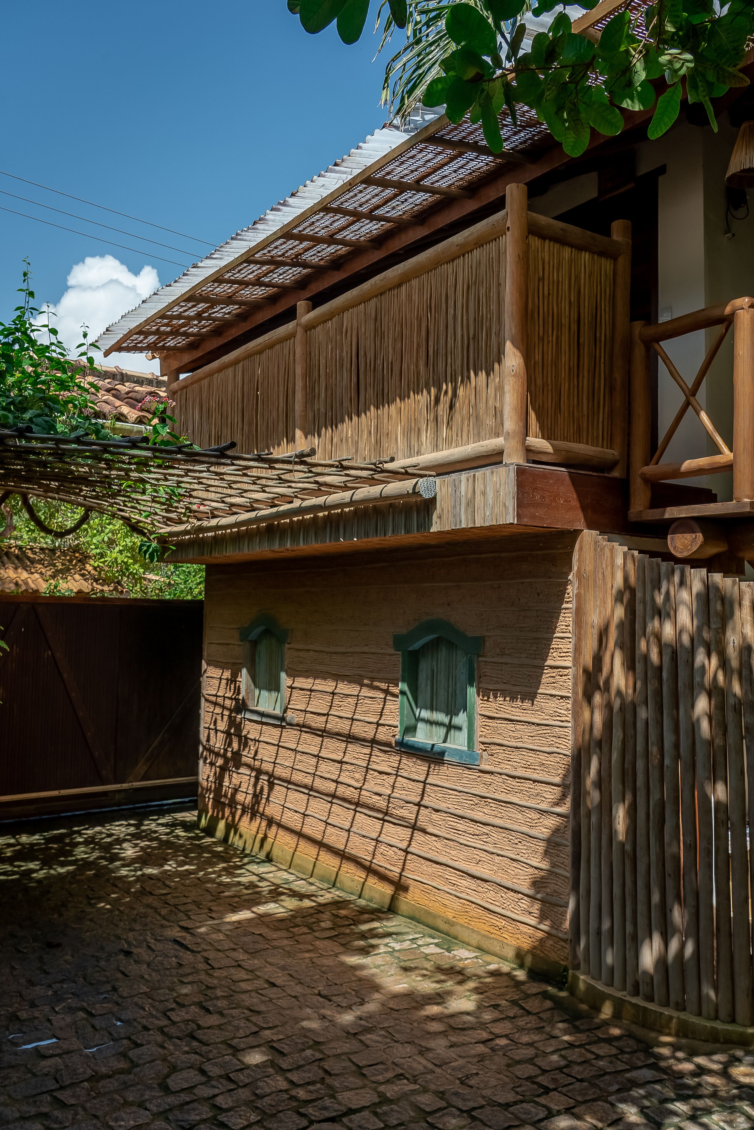 Une maison rustique en bois, avec un toit en tuiles, un balcon et un mur en briques.