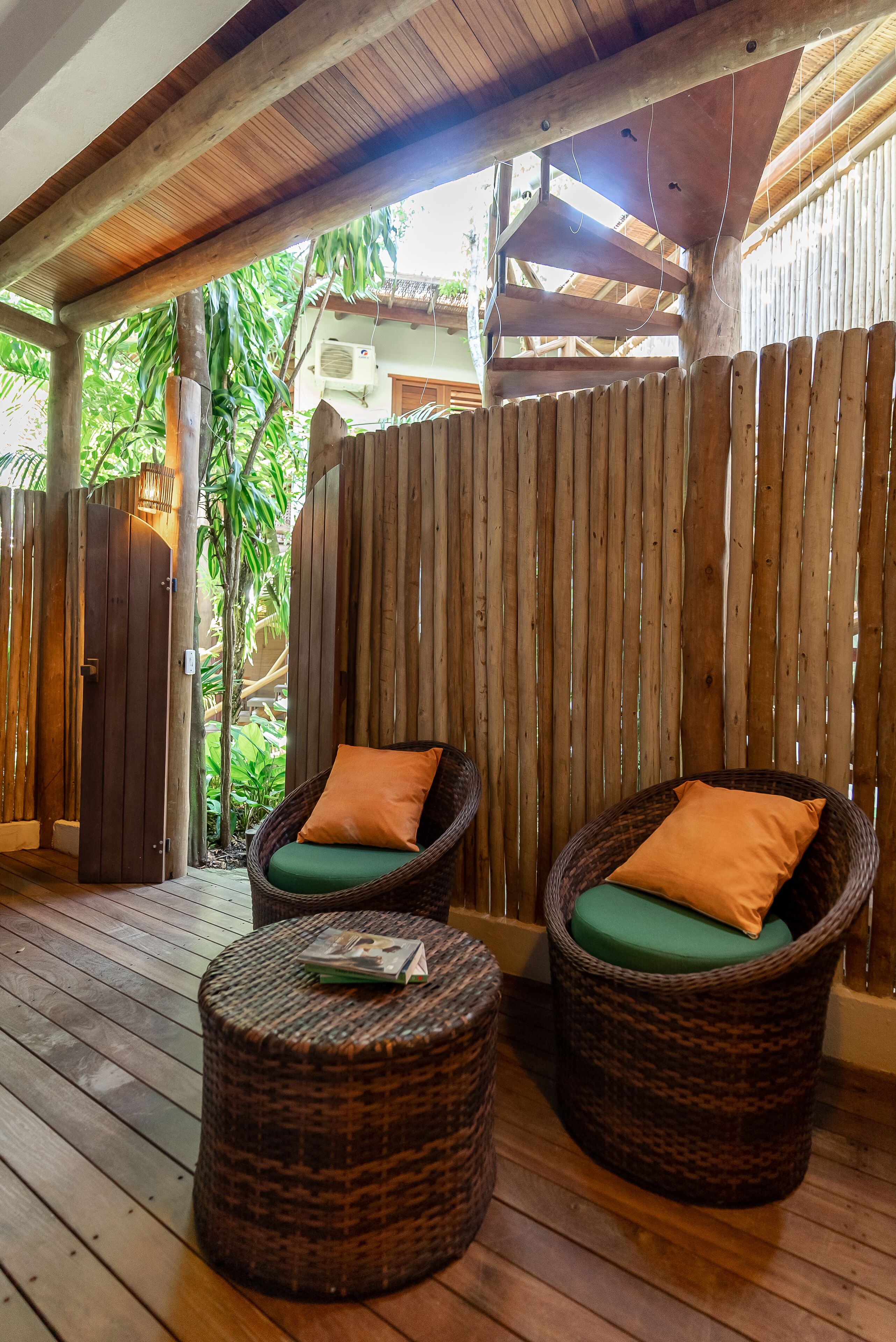 A covered outdoor seating area with wicker furniture and a wooden floor.