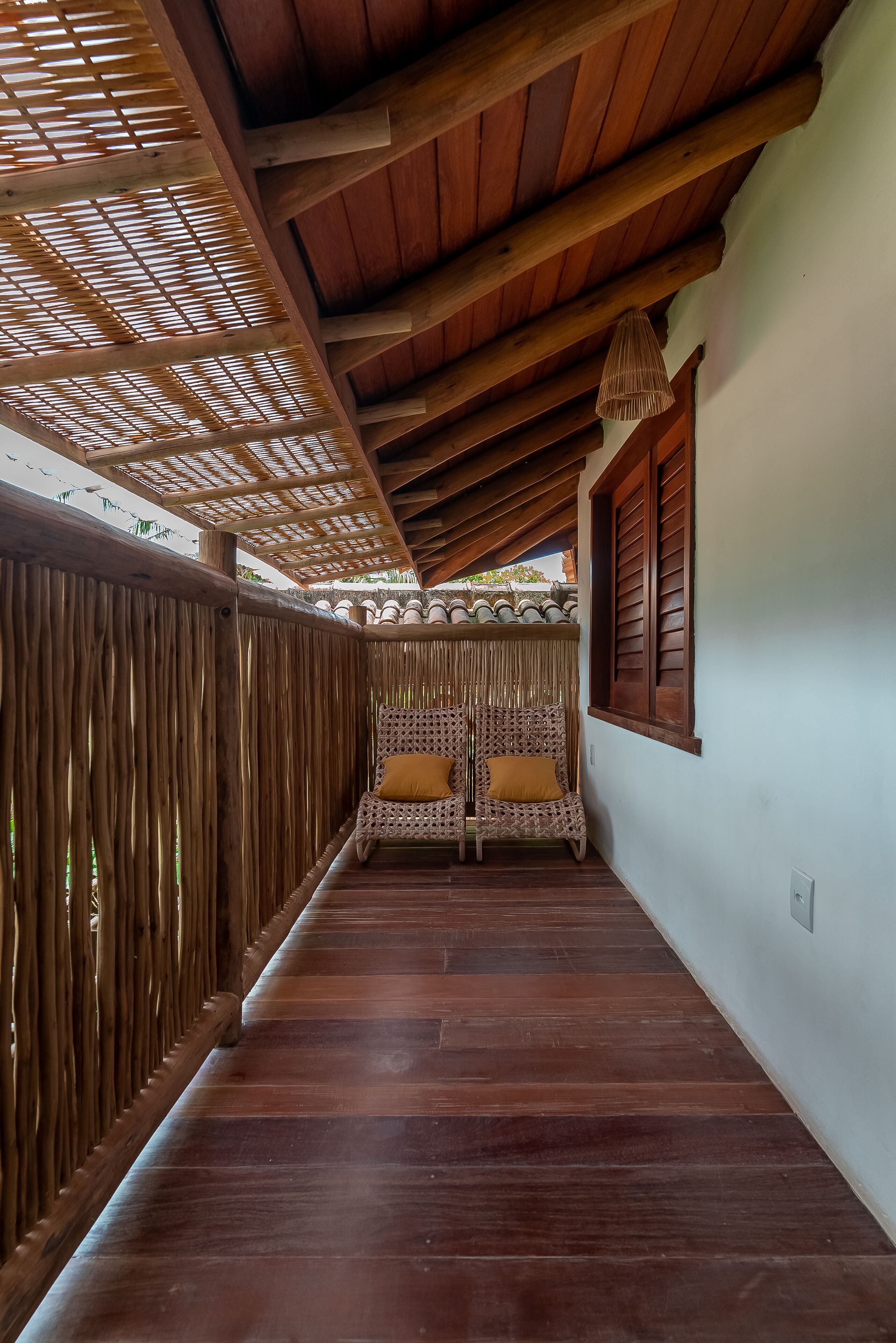 Un pasillo de madera con techo tejido y un banco con cojines.