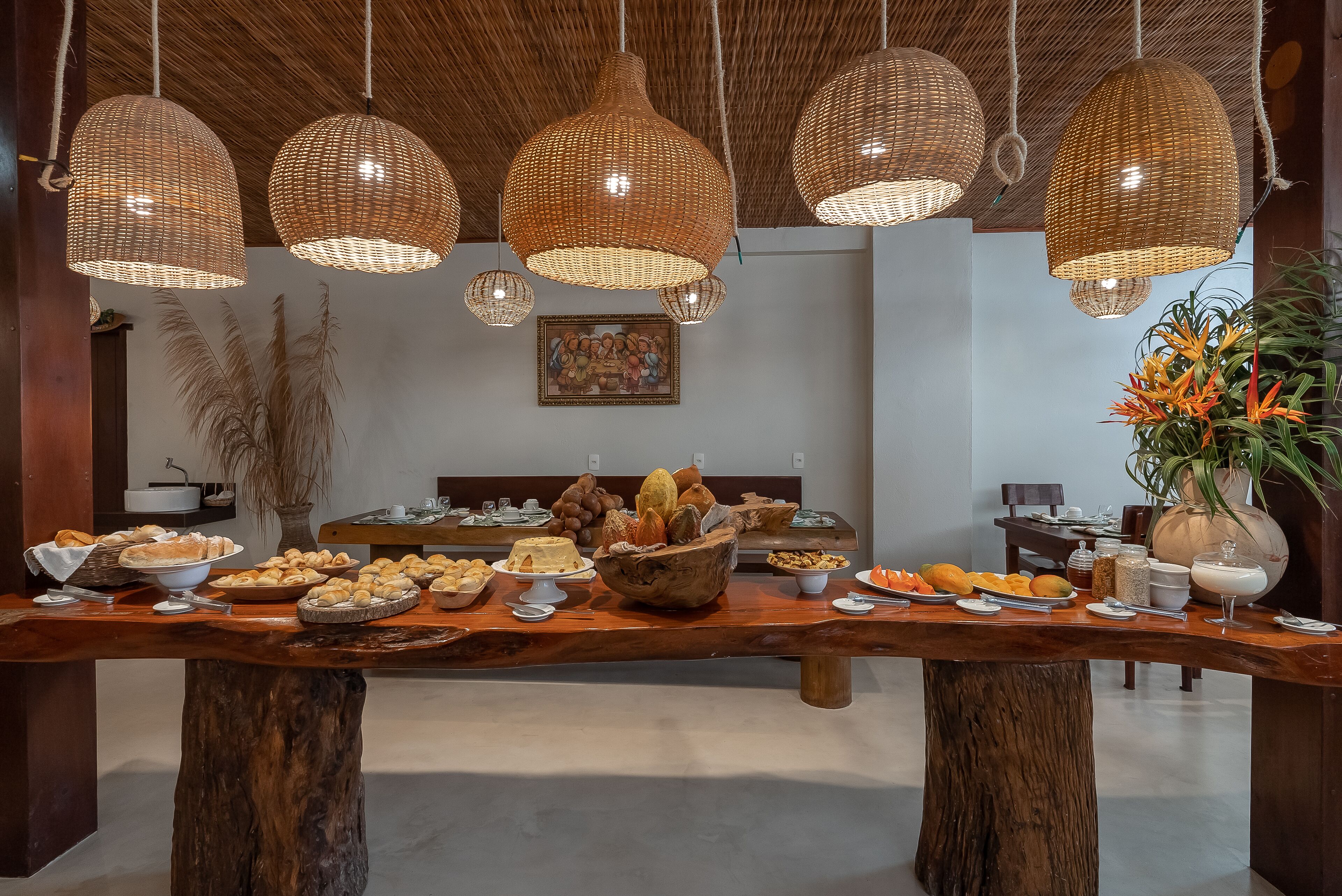 Una mesa de buffet con diversos alimentos y un comedor con lámparas colgantes de mimbre.
