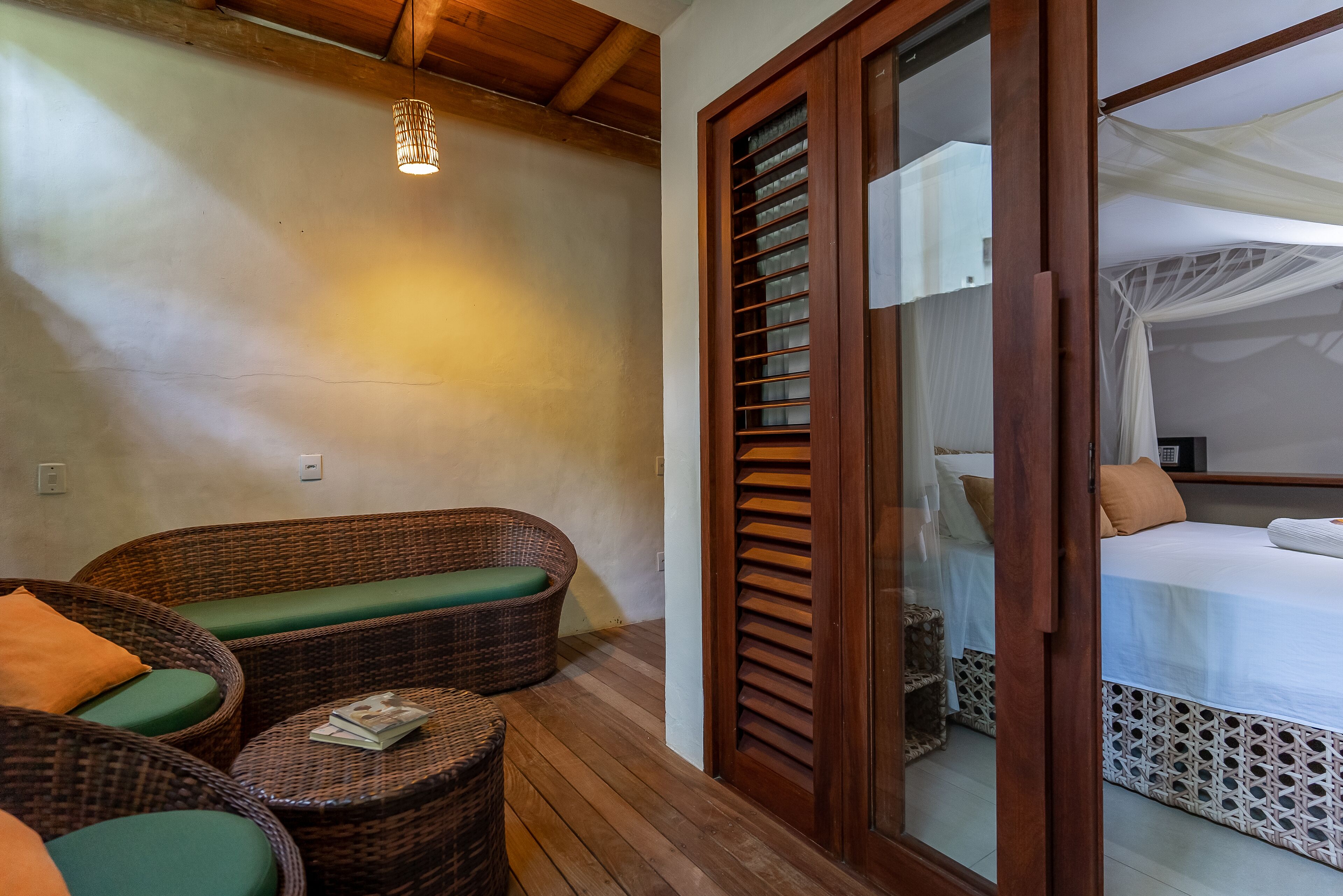 A room with wicker furniture, a wooden ceiling, and a bed with white bedding.
