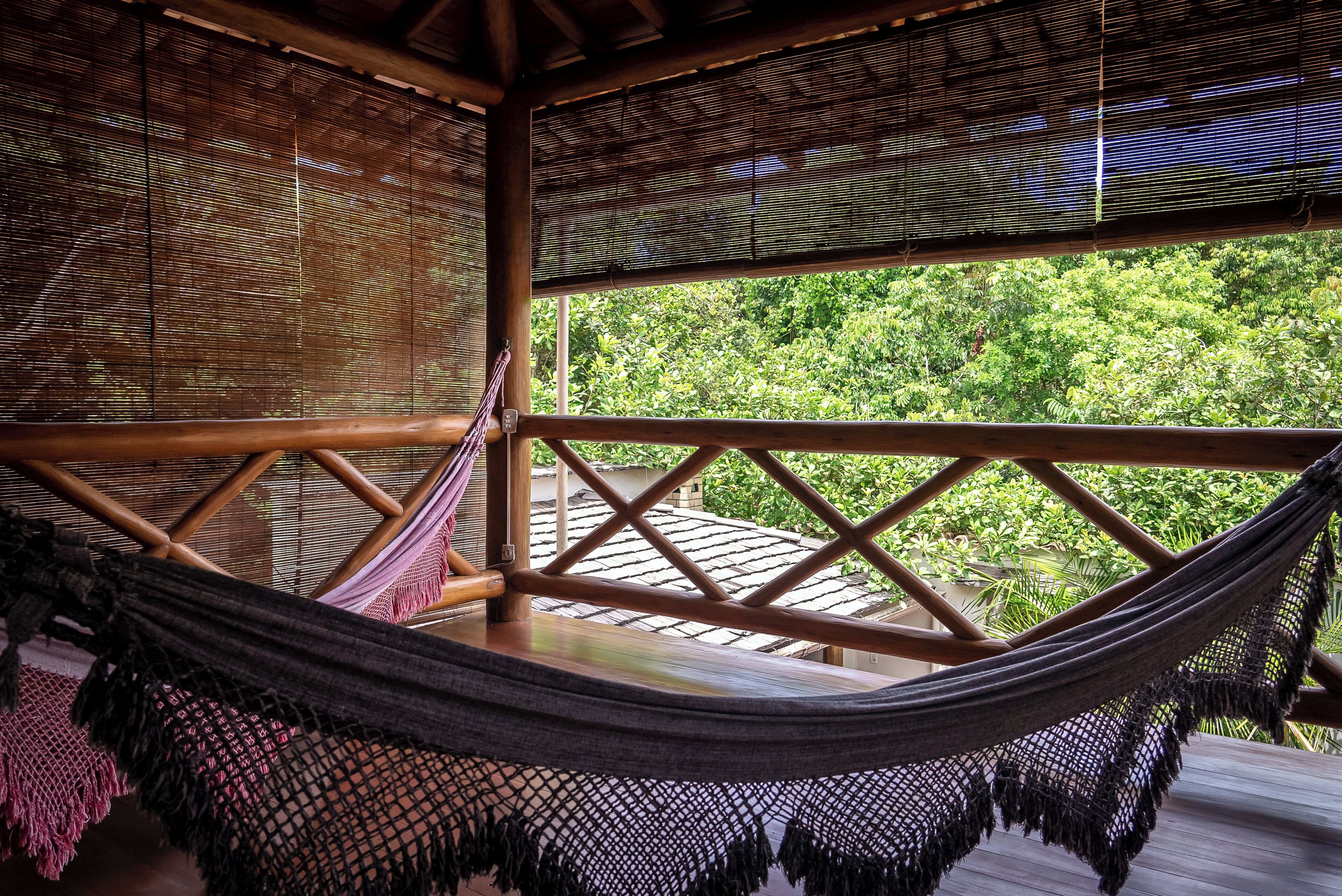 A hammock on a wooden deck with a view of lush greenery.
