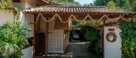 A traditional house with a tiled roof, a wooden gate, and a signboard.