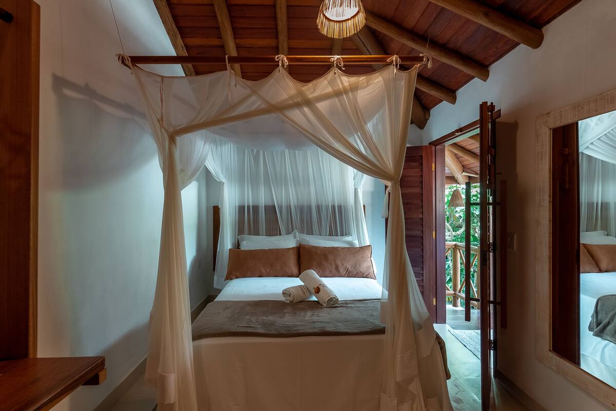 Ein Bett mit Baldachin, Kissen und einem zusammengerollten Handtuch.