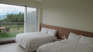 A hotel room with two beds, a large sliding glass door leading to a balcony with chairs, and a view of greenery. - Sunrise Villa (Beinan)