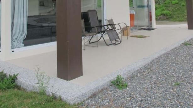 A modern house with a covered patio, large glass doors, and a seating area with chairs. - Sunrise Villa (Beinan)