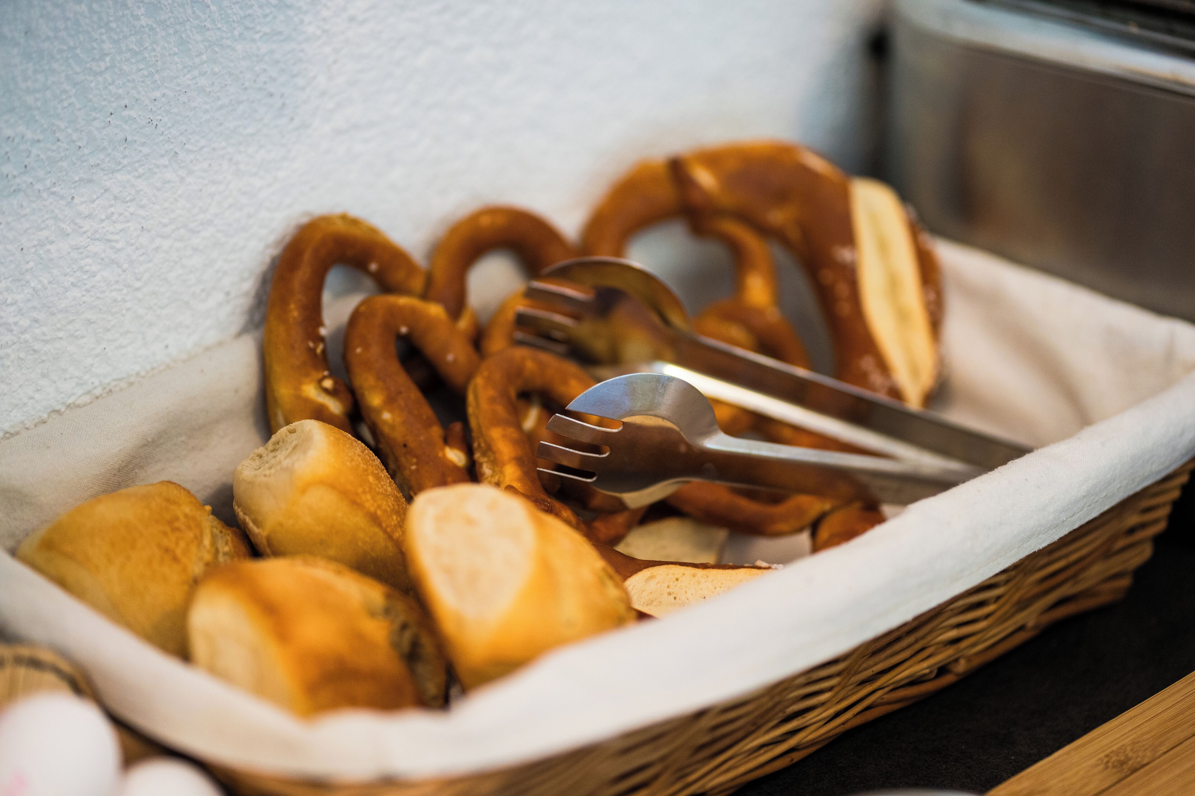 Una cesta con pretzels y palitos de pan sobre una mesa.