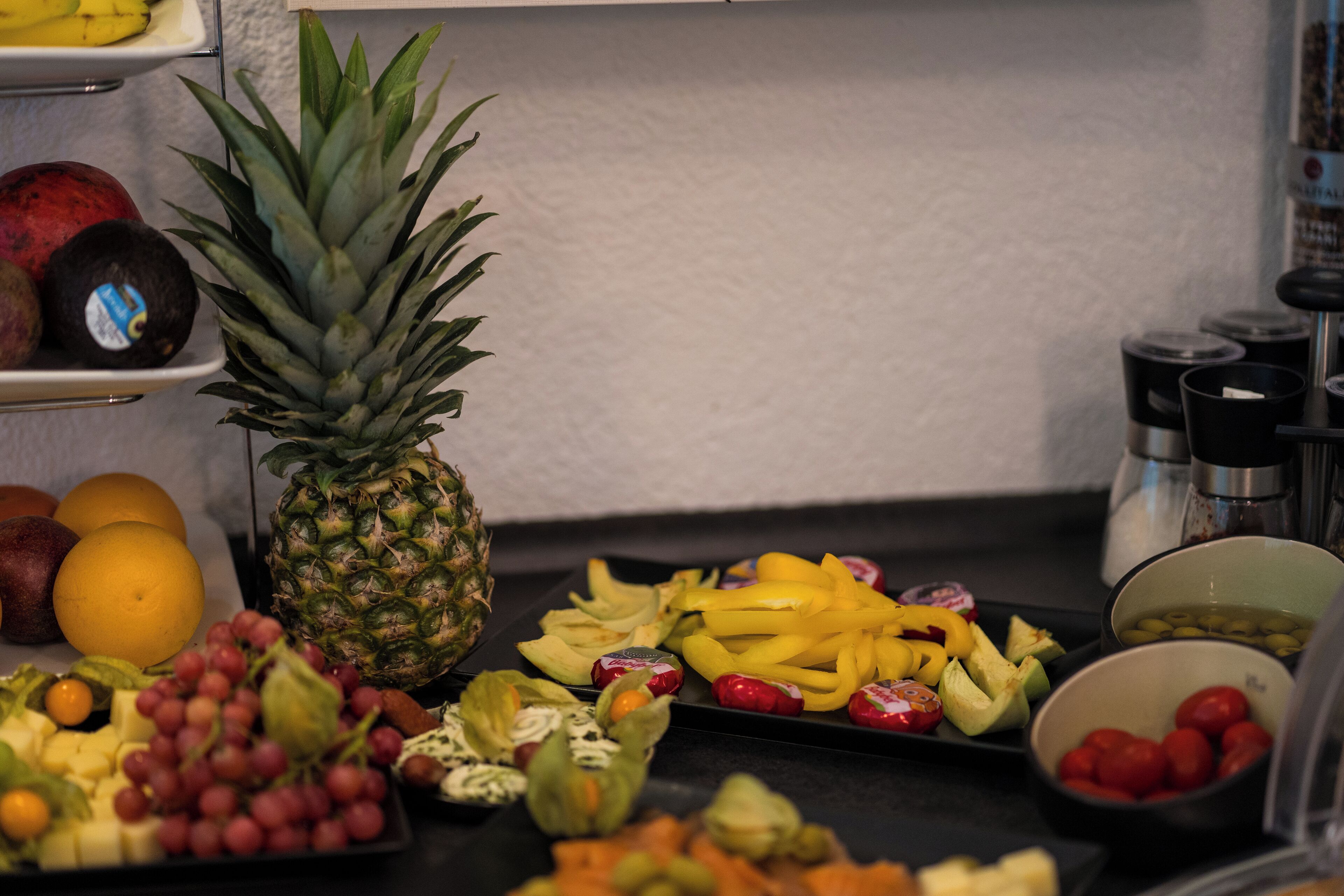 A variety of fruits and vegetables on a tray, including grapes, pineapple, and tomatoes.