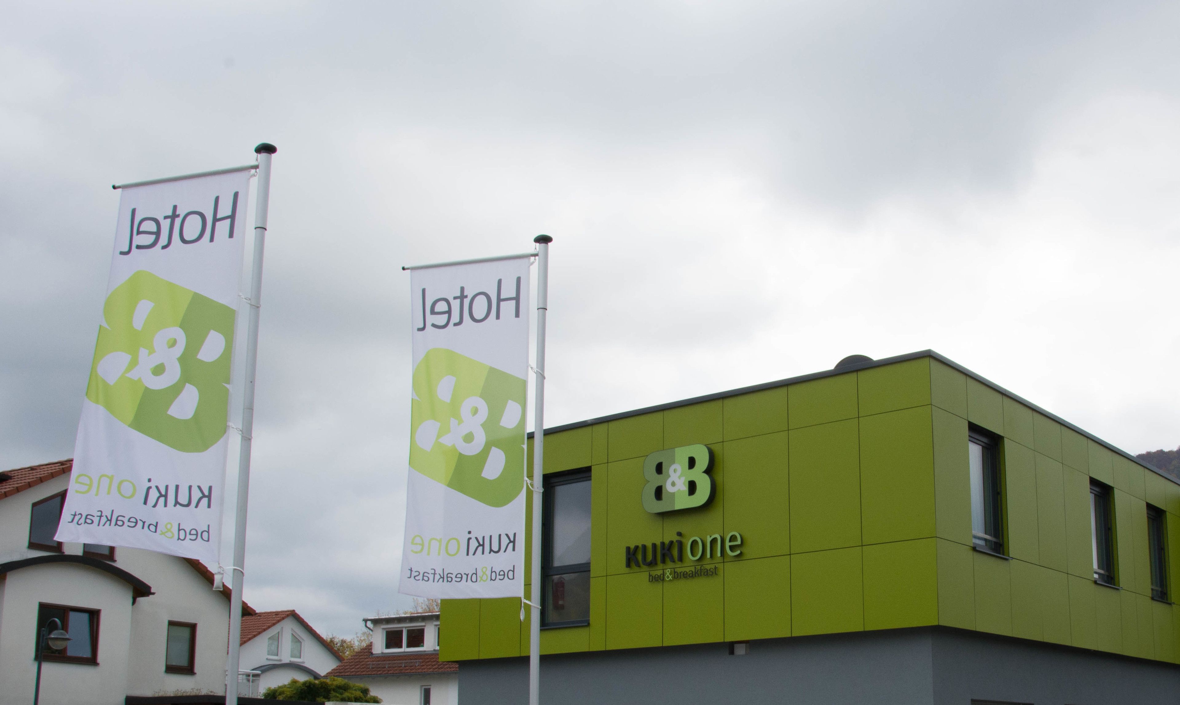 A building with a green facade and a sign that reads "kukioone bed & breakfast".