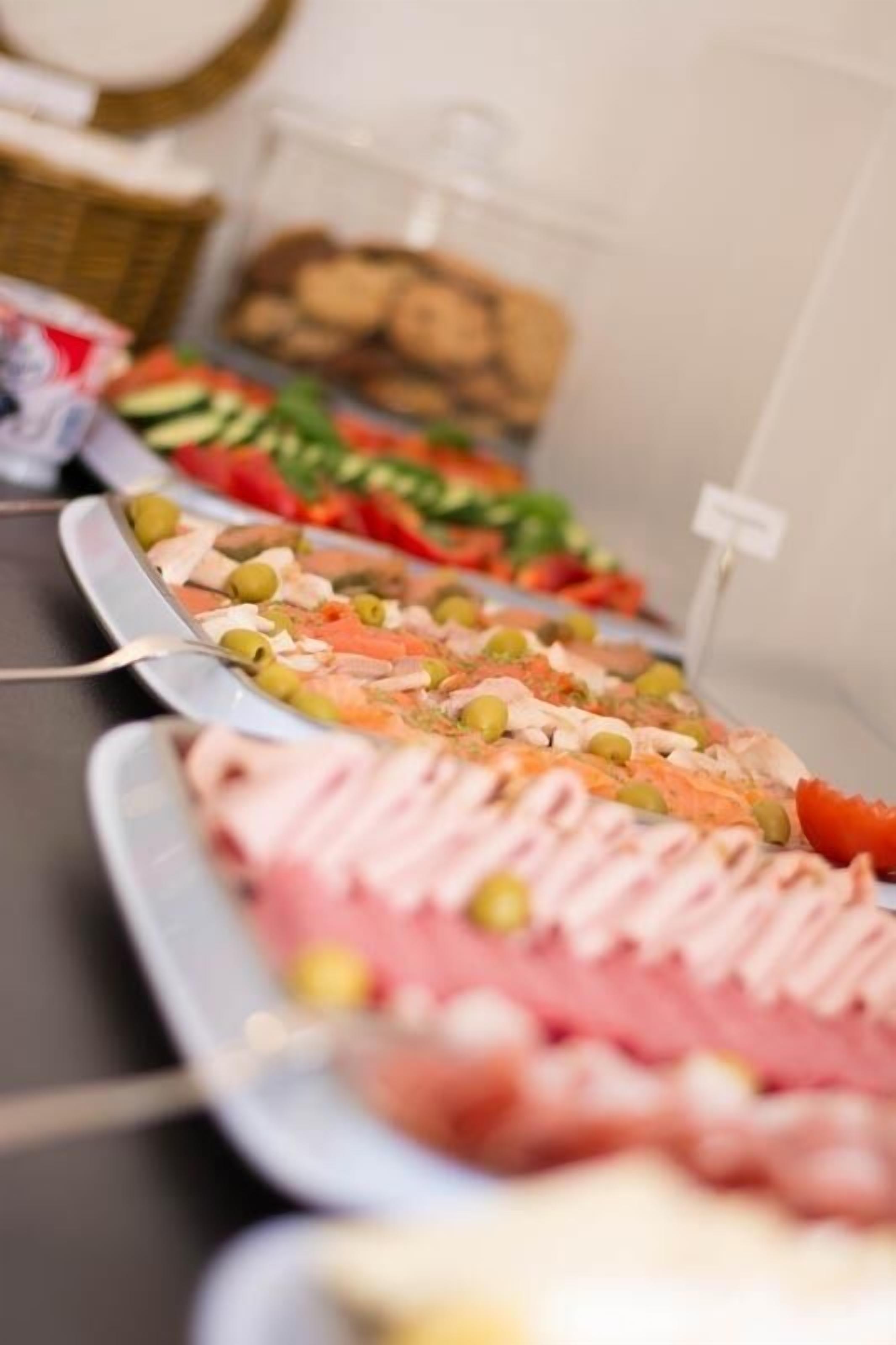 Un bufé con diversas opciones de comida, incluyendo carnes, quesos y verduras.