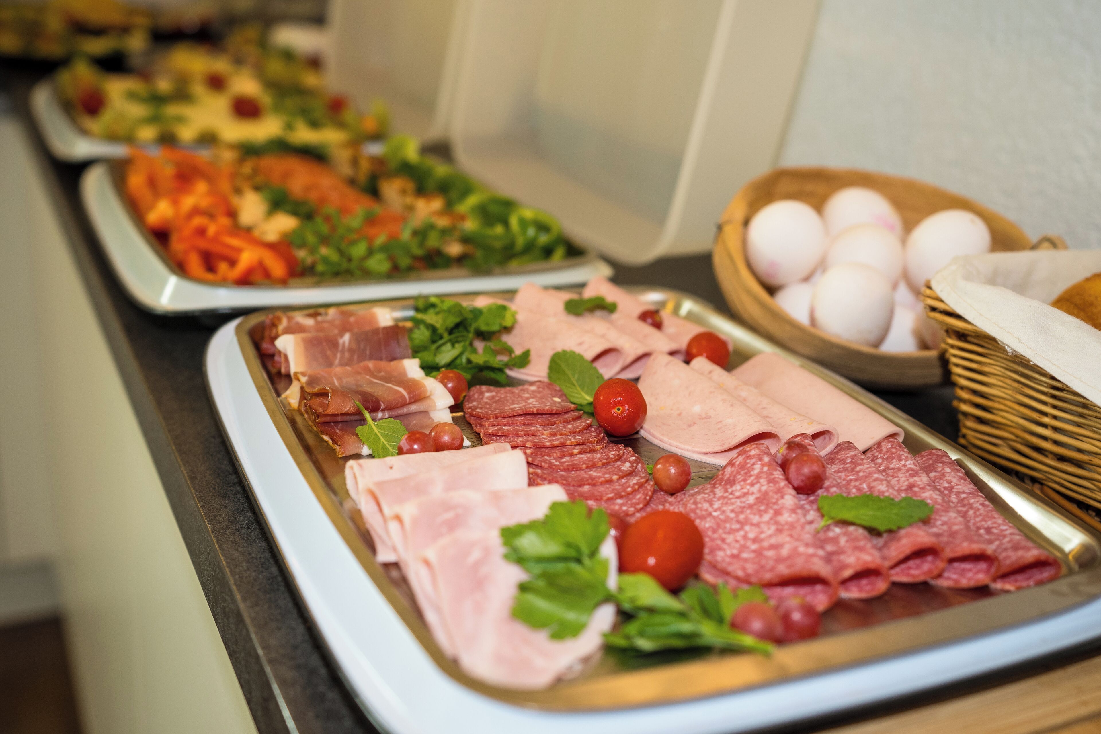 A buffet with various meats, vegetables, and eggs.