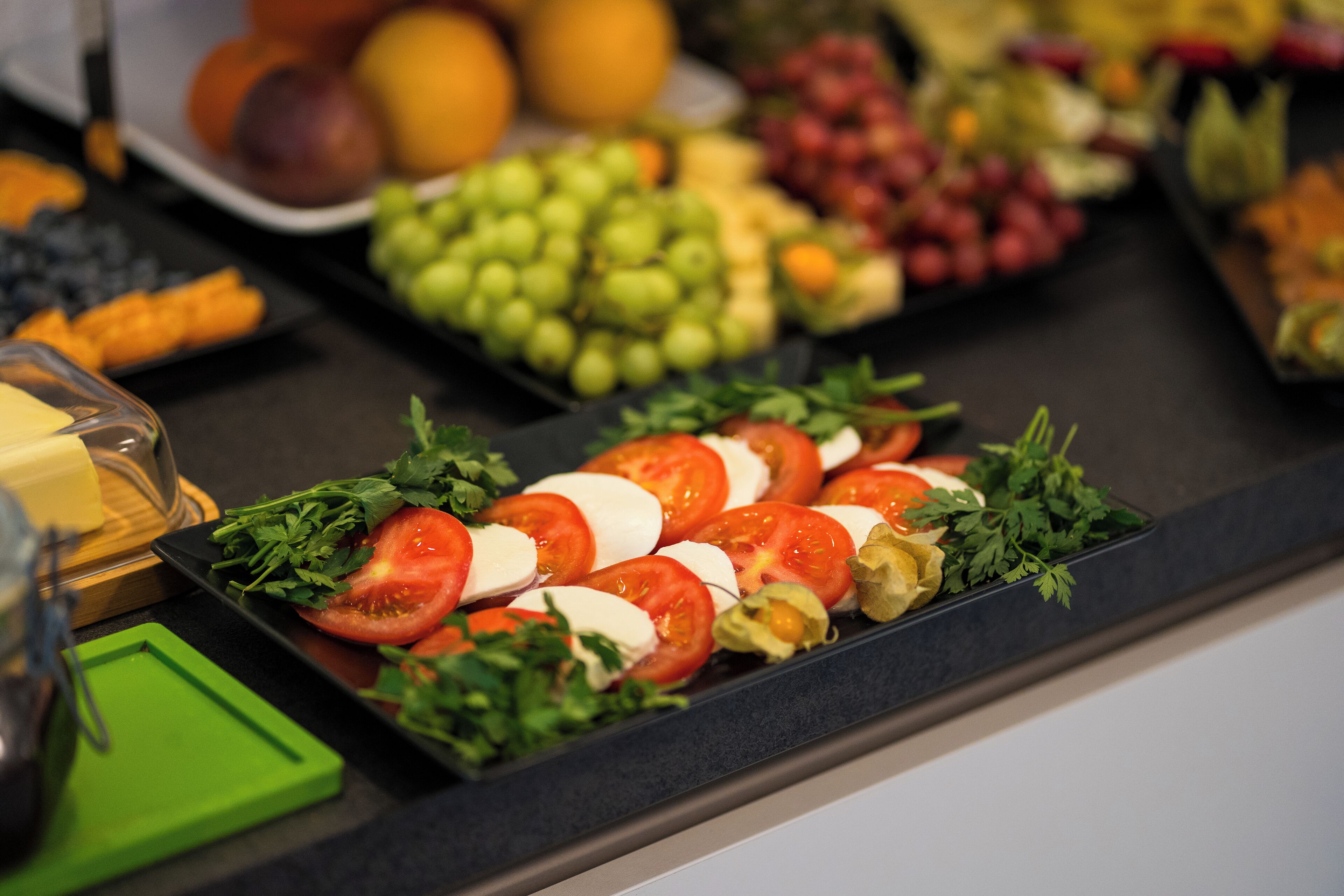A buffet with various fruits, vegetables, and cheeses.