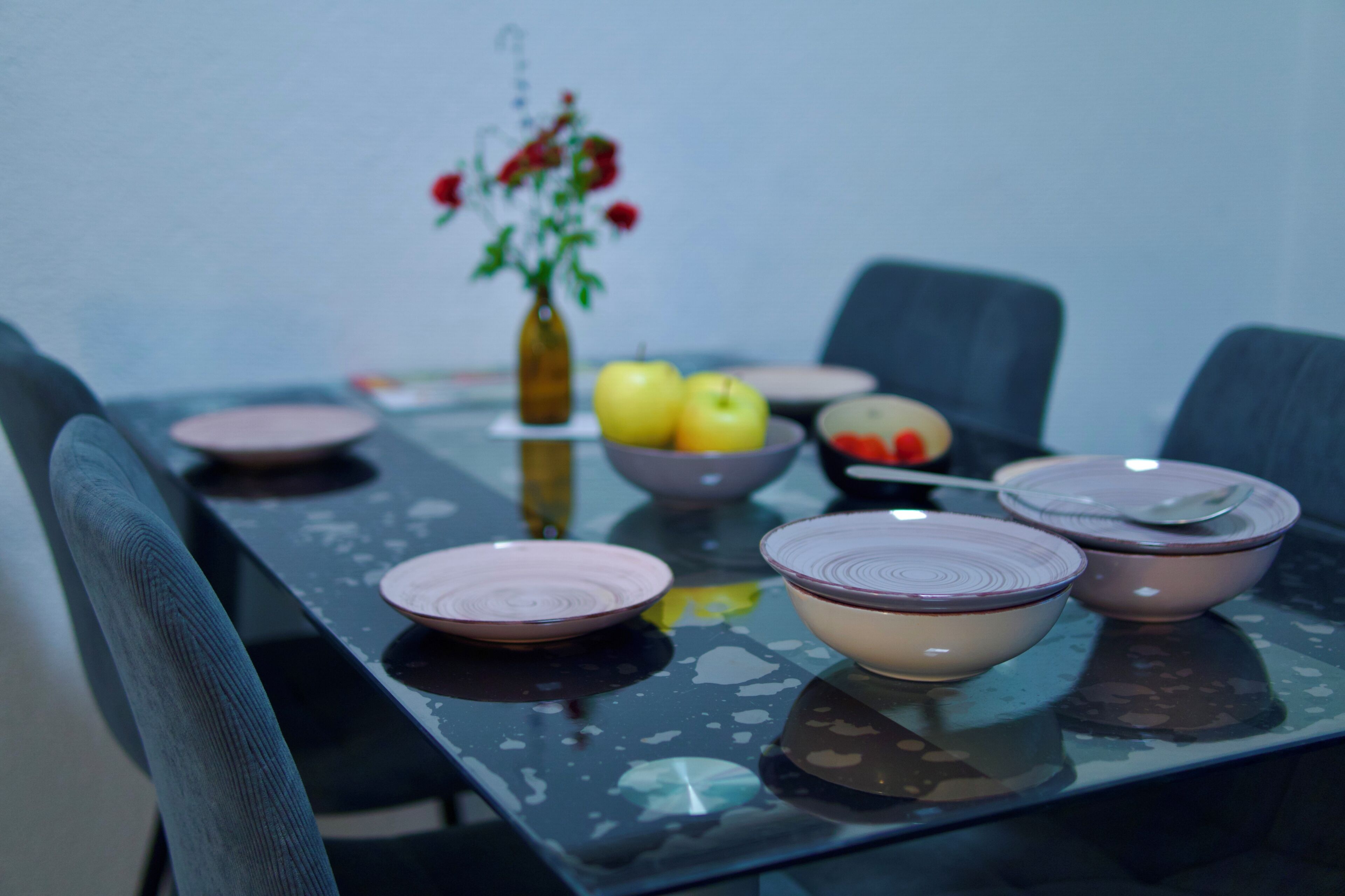 A dining table with pink plates, bowls, and a vase with flowers.