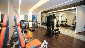 Een moderne sportschool met cardioapparatuur, krachttoestellen en een spiegelwand.
