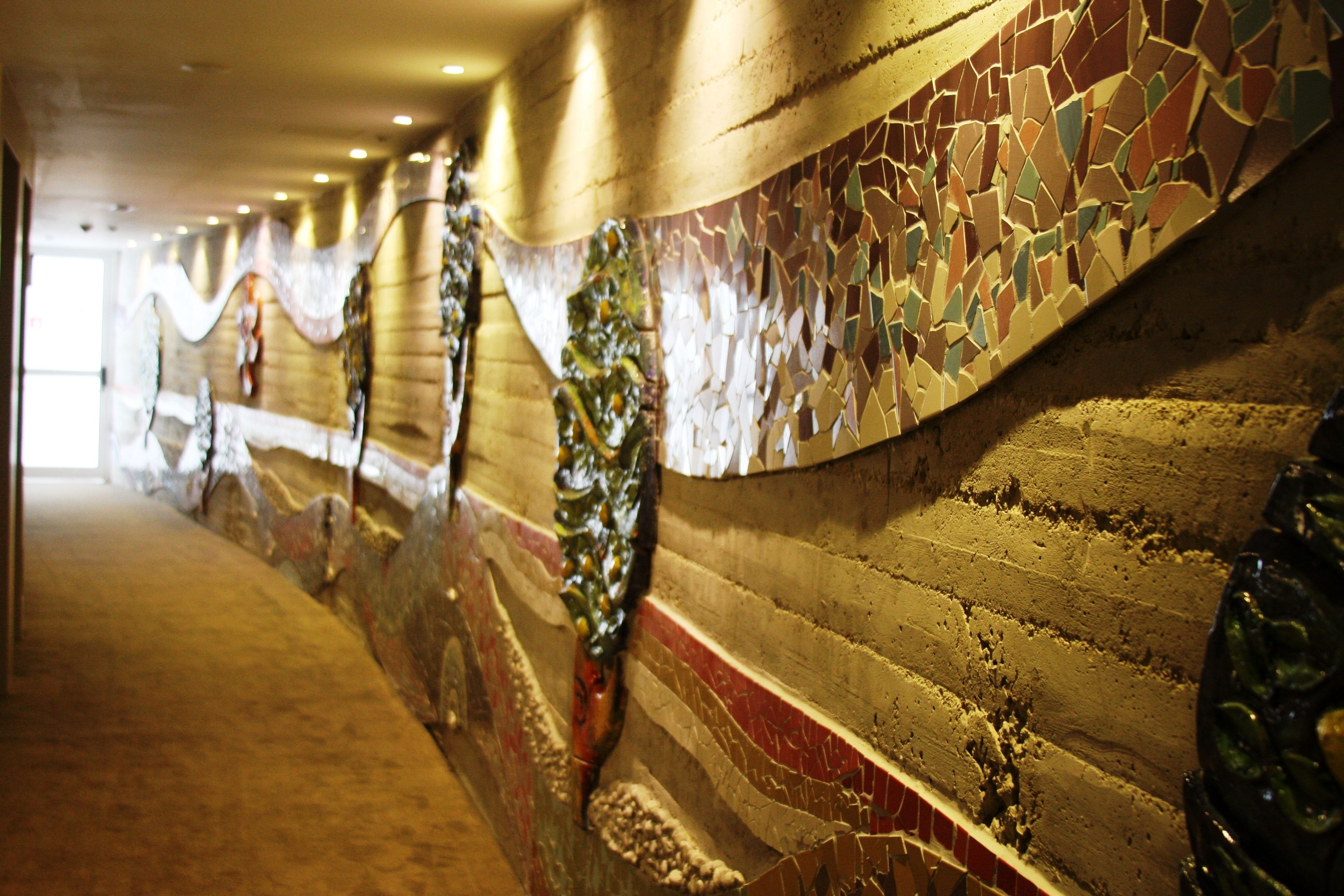Un pasillo con un muro de mosaico y un techo curvo.