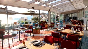 Un restaurant en plein air avec des tables et des chaises, un toit en verre et une vue sur la ville.