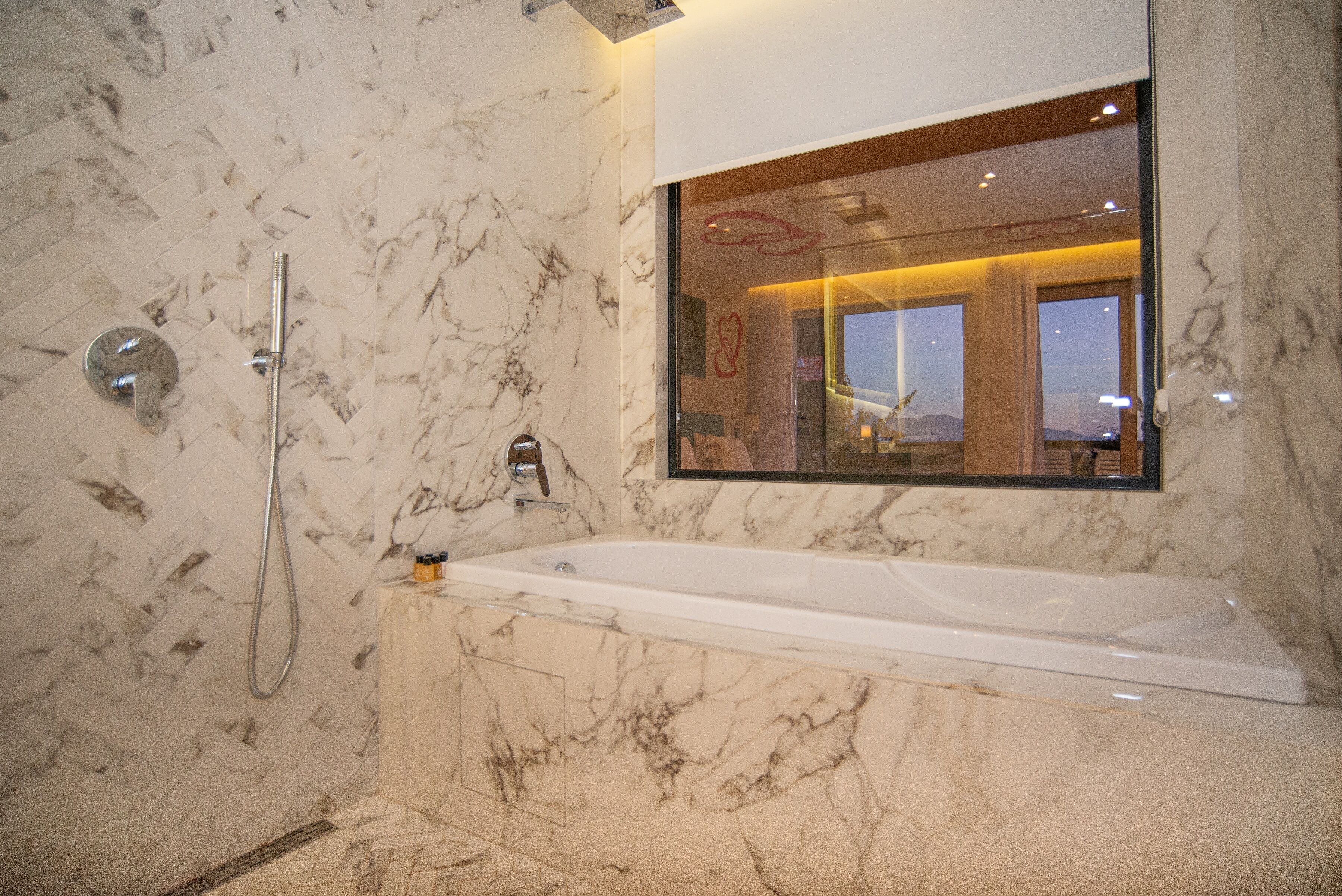 A modern bathroom with a marble floor, a bathtub, and a shower.
